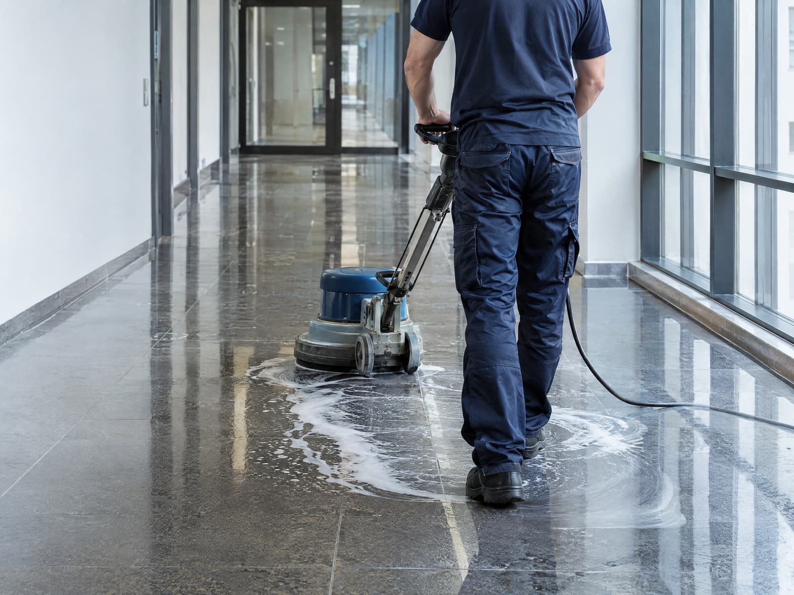 Grundreinigung eines Steinbodens mit Einscheibenmaschine im Bürogang